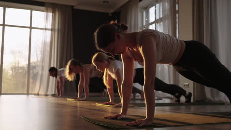 Eine-Gruppe-Von-Frauen-Unterschiedlichen-Alters,-Dick-Und-Dünn,-Praktiziert-Gemeinsam-Mit-Einem-Lehrer-Yoga-Bei-Sonnenuntergang-In-Zeitlupe.